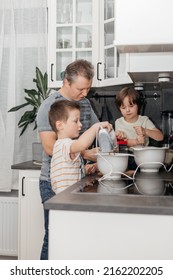 Dad and sons knead and prepare dough for baking muffins or biscuits. Dad helps and teaches children to cook. Time with family. little helpers