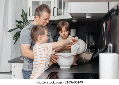 Dad and sons knead and prepare dough for baking muffins or biscuits. Dad helps and teaches children to cook. Time with family. little helpers