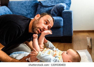 Dad Struggling With His Baby Daughter To Change Dirty Diapers Putting Faces Of Effort, Concept Of Fatherhood.