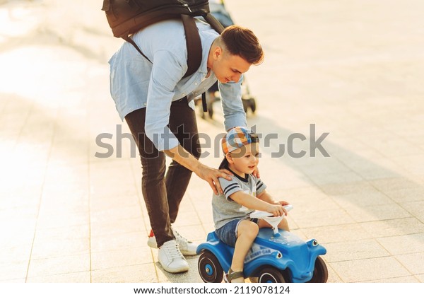 Dad teaches
his little son to ride a children's car in the park, keep balance,
have fun with the family. Father and son in the park, the boy is
driving a children's car. Father's
day