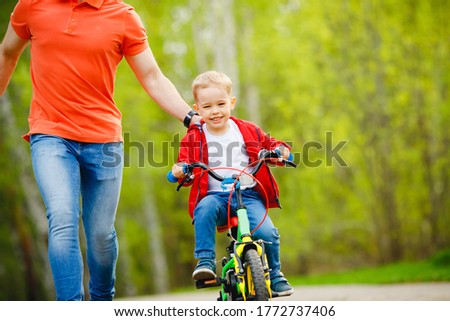 Dad teaches little son to ride bike in park, keep balance, have fun family. Father day concept.