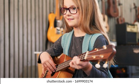 Dad teaching guitar and ukulele to his daughter.Little girl learning guitar at home.Close up.Ukulele class at home. Child learning guitar from her father - Powered by Shutterstock