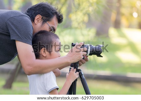 Dad is teaching photography to his son
