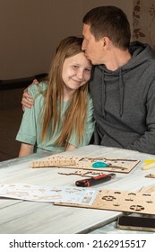 Dad And Teenage Daughter Work Together On DIY Homework Project. Dad Hugs And Kisses Smiling Daughter. Happy Family Concept. Father's Day Friendship Day