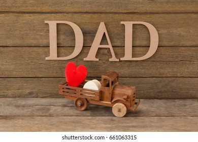 Dad text by heart shape in toy truck on wooden table - Powered by Shutterstock