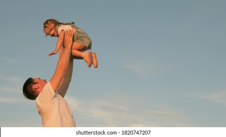 Dad Throws Up A Happy Daughter In Blue Sky. Happy Family Travels. Father And Small Healthy Child Play Together, Laugh And Hug. Baby In Arms Of Parent. Dad Day Off. Concept Of A Happy Family.