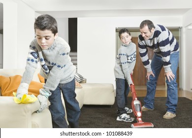 Dad And Twin Sons Cleaning Their Home's Living Room.