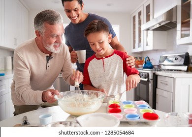 Dad Watching His Son Making Cakes With Grandad At The Kitchen Table, Close Up