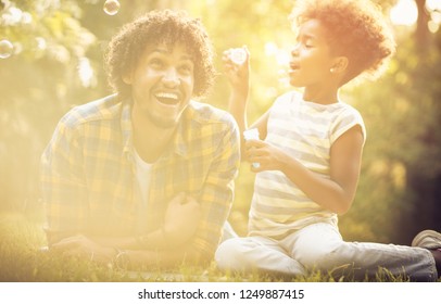 Dad, You Thought Of Desire For Every Bubble. African American Daughter And Her Father Playing With Water Balloons In Park.