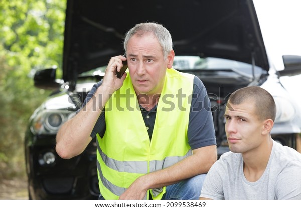 dad and young man with\
broke down car