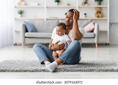 Daddy Blues. Stressed Young Black Father Sitting With Crying Infant Baby On Floor At Home, Depressed Upset African American Dad Touching Head, Suffering Paternity Leave Troubles, Copy Space - Shutterstock ID 2079163072