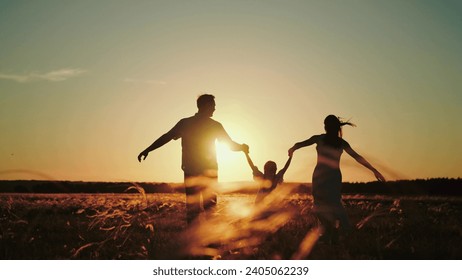 Daddy brings wife with daughter for run in evening field to pick fresh flowers to make bouquet for girls. Daddy and mother run happily with jumping daughter holding hands wishing evening to last - Powered by Shutterstock