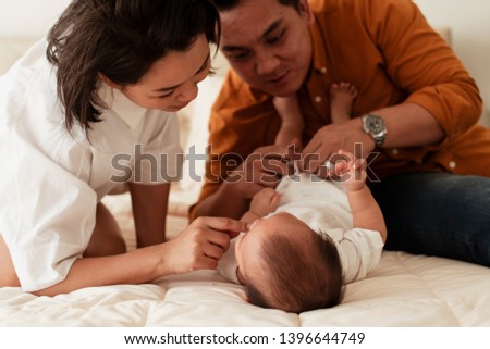 Daddy changing son clothes helping by mom drawing attention.