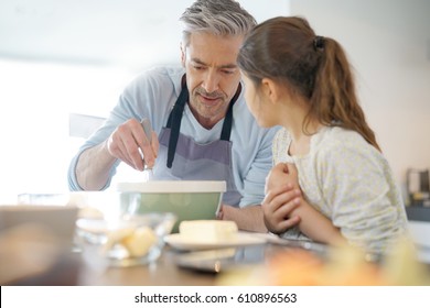 Daddy With Daughter Baking Cake Together In Home Kitchen