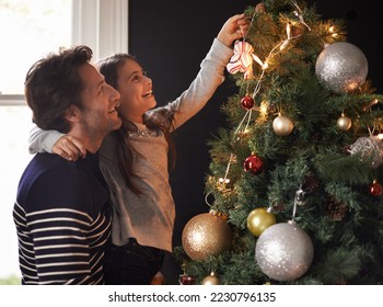 Its a daddy daughter thing. Shot of a young girl and her father decorating the Christmas tree together. - Powered by Shutterstock