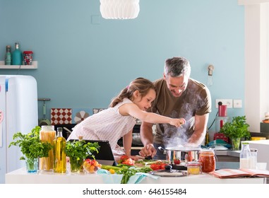 Daddy and his little daughter cooking bolognese sauce for spaghetti in the kitchen, there is steam escaping from the pan on cooking plate - Shutterstock ID 646155484