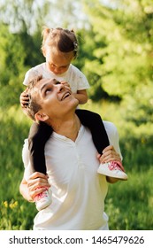 
Daddy Holds His Daughter On His Shoulders In White T-shirts. Looks At Her.