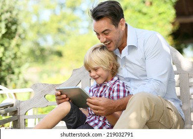 Daddy And Son Playing With Tablet Outside