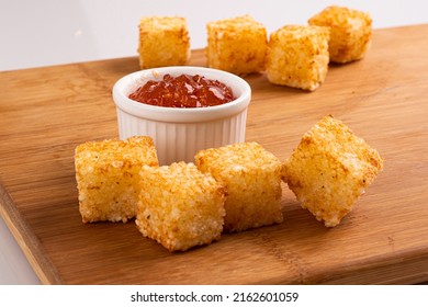 Dadinho de Tapioca - Traditional  fingerfood from Brazil  - Squares of tapioca and cheese served with pepper jelly. Wooden table. Space for text - Dice of tapioca - Dadinho de tapioca