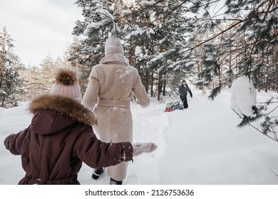 Dads Roll Their Daughter On A Sleigh, Mom Runs With Her Daughter Through The Snowy Forest. High Quality Photo