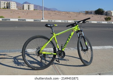 Dahab, Egypt - 14.02.2022: A bicycle standing near the road in the background of residential buildings and distant mountains
