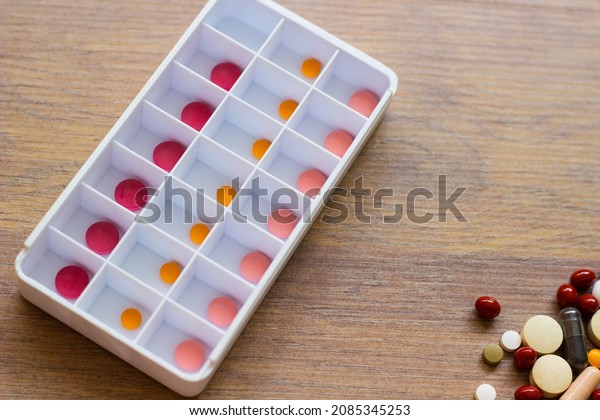 Daily\
pill box. Pills and tablets over wooden background\
