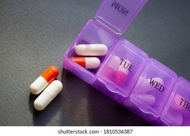 Daily Pill Dispenser With Assorted Meds On Dark Background. Pill Box With Days Of The Week.