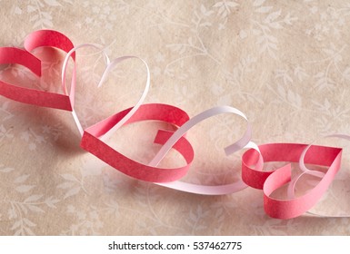 Dainty Chain Of Alternating Red And White Paper Hearts Symbolic Of Love And Romance On Neutral Floral Wallpaper Background With Copy Space For Your Valentines Message To A Sweetheart