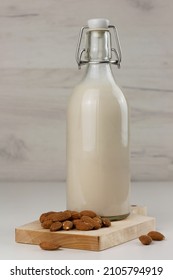 Dairy free almond milk in a bottle and nuts on light background. Vertical orientation