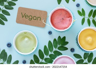 Dairy Free, Fruit Ice Cream Or Frozen Yogurt. Summer Food Composition With Various Homemade, Vegan, Fruit Ice Cream, Leaves And Blueberries On A Blue Background With Inscription Vegan. Flat Lay