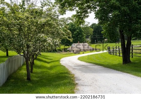 The dairy at Hampton National Historic Site in Towson, Maryland. The farm side of the park shows low dairy building built over a spring to keep milk cold. Winding path, flowering trees and fences. 