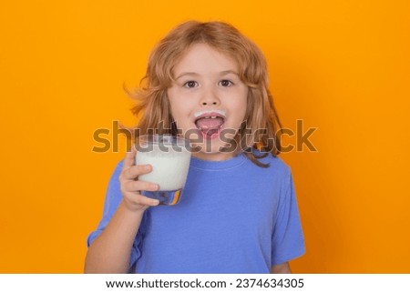 Dairy milk. Portrait of child drinking milk, yellow isolated studio background. Kid with glass of milk and milk moustache.