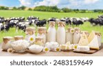 Dairy products. Bottles of milk, cottage cheese, yogurt, various cheese, mozzarella, butter on wooden table on meadow with grazing cows background
