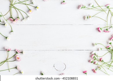 Daisy flowers on wooden white background. Frame of summer flowers. Top view, flat lay