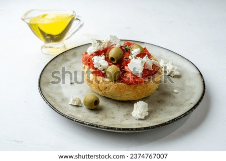 Dakos or ntakos, Greek appetizer of bread, tomatoes and olive oil with raw feta, light table.