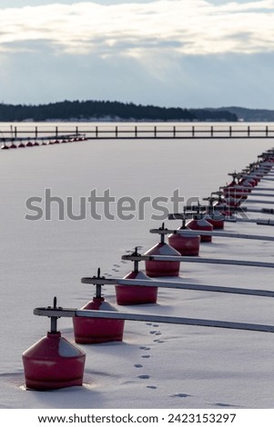 Dalaro, Sweden A small boat dock with red buoys with no boats in the ice on the Baltic Sea.