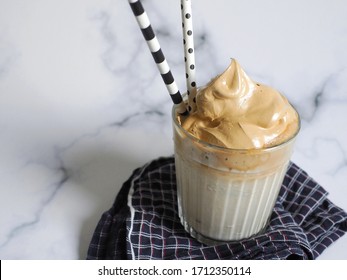 Dalgona Coffee On White Marble Background With Napkin And Fancy Paper Straws, A Trend That’s Inspired By South Korean Candy And Spread Over The Internet Since People Stay Home During COVID-19 Pandemic