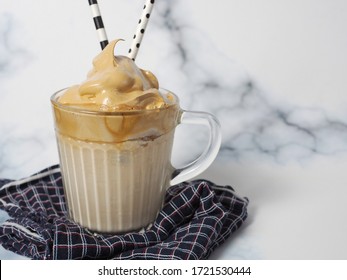 Dalgona Coffee On White Marble Background With Napkin And Fancy Paper Straws, A Trend That’s Inspired By South Korean Candy And Spread Over The Internet Since People Stay Home During COVID-19 Pandemic