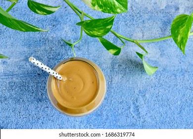 Dalgona Iced Coffee. Viral Korean Drink Frothy Whipped Coffee. Blue Background. Flat Lay