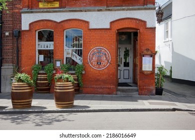 DALKEY, CO. DUBLIN, IRELAND - JULY 02, 2022: 1909 Restaurant And Wine Bar Exterior In Dalkey Town. Restored Building With Colorful Logo Painted On The Wall And Potted Flowers On Barrels At The Front.