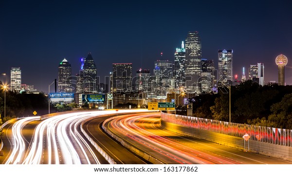 DALLAS, USA - OCTOBER 25: Dallas skyline\
by night on October 25, 2013 in Dallas, USA. The rush hour traffic\
leaves light trails on I-30 (Tom Landry)\
freeway.
