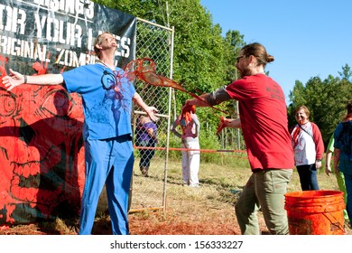 DALTON, GA - SEPTEMBER 14:  A Man Dressed In Medical Scrubs Gets Fake Blood Splattered On Him So He Can Menace Runners In The Run For Your Lives 5K Event, On September 14, 2013 In Dalton, GA. 
