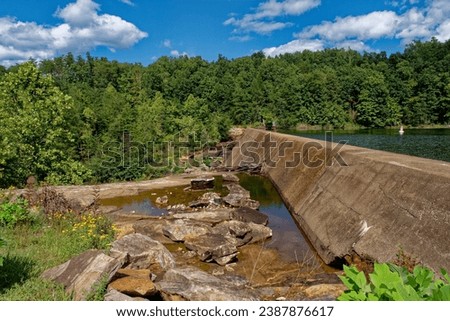 A dam at a lake with a cement wall separating the water levels at meadow creek park in Monterey Tennessee on a bright sunny day in early autumn