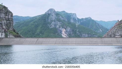 Dam On Mountain Komani Lake In Albania Mountains, Summer. Beautiful Mountain Nature Around Water Dam. Travel In Alps Mountains Covered With Green Plants. No People