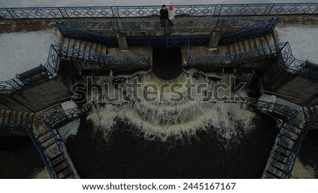 A dam on a reservoir with an open sluice, a small waterfall. Winter