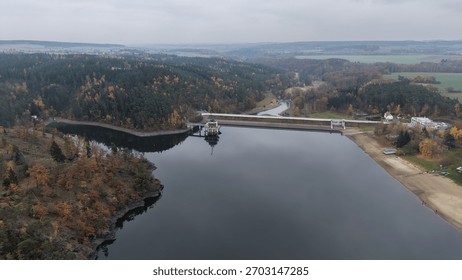 Dam structure with control building and spillway in autumn forest landscape. Perfect for engineering background or environmental report - Listany, Czech - Nov,8,2025