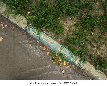 Damadged Old Curb Painted Aquamarine Needs To Be Replaced. Yellow Leaves On Asphalt. Top View