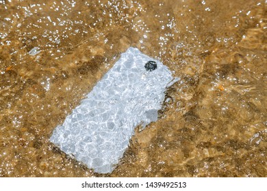 Damage and wet smart phone dropped on flooding with water of sea background