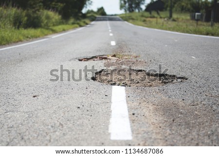 Damaged asphalt pavement road with potholes.