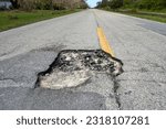 Damaged asphalt road with deep pothole on american highway surface. Ruined roadway in urgent need of repair